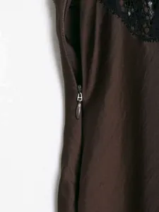 Détail d'une robe en satin marron foncé avec dentelle noire et fermeture éclair invisible