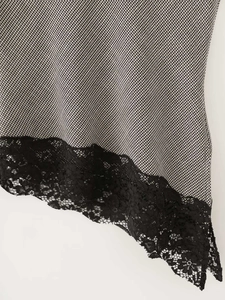 Macro detail of houndstooth fabric with black floral lace trim on the hemline