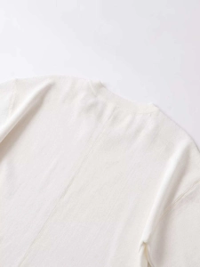Détail de l'encolure ronde côtelée et de la couture arrière sur ce pull en maille crème