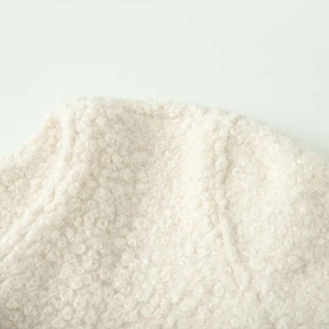 Detailed macro view showing soft boucle texture and stitching of the cream jacket hood