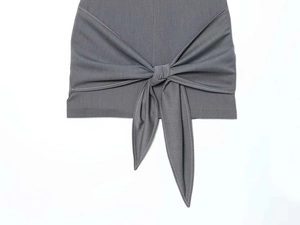 Detail of grey dress showing contrast white stitching and decorative waist bow knot