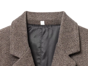 Détail du blazer en laine à chevrons montrant la texture brune, le revers et la doublure
