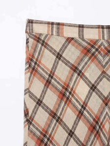 Detailed macro view of the brown and orange plaid linen texture on a midi skirt