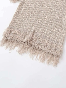 Détail du tricot beige clair montrant les finitions à franges et la texture du tissu