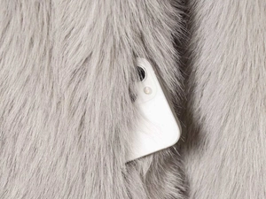 Detail of side pocket on light grey faux fur coat with smartphone for size reference