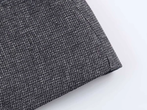 Macro detail of the grey textured faux fur fabric and precise stitching on the blazer