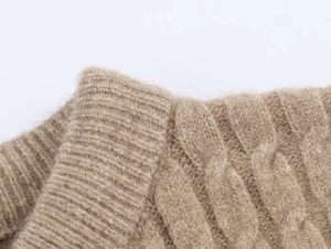 Dettaglio della trama a trecce e scollo a coste su un maglione beige in misto cashmere