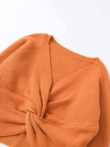 Detail view of caramel knit sweater featuring V-neckline and decorative front knot design