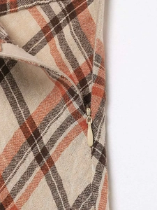Detail of invisible zipper closure and plaid fabric texture on the midi skirt