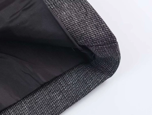 Close-up of textured grey tweed fabric with smooth black lining on a tailored jacket