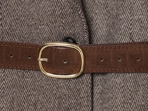 Detail de ceinture en daim marron avec boucle doree sur une veste a chevrons