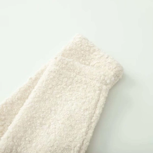 Detailed macro view of the cream white bouclé texture and stitching on the jacket sleeve