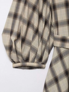 Detailed view of checkered summer dress featuring puff sleeves and matching belt buckle