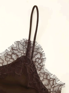 Macro detail of dark brown satin dress with intricate eyelash lace trim and thin straps