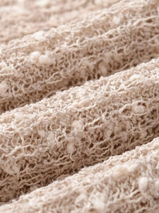 Gros plan sur la maille ajourée beige avec pompons décoratifs et détails de glands