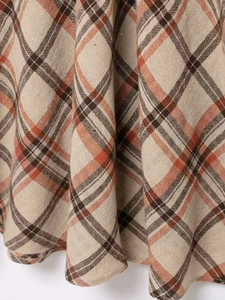 Detailed close-up of retro plaid fabric in beige and orange with linen texture