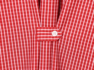 Macro shot of red and white gingham shirt fabric with button strap and white resin button