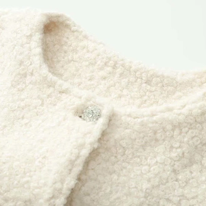 Close-up of cream textured faux shearling jacket with a sparkling rhinestone button