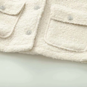 Detail of creamy white boucle jacket with sparkling rhinestone flower buttons and pockets