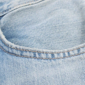 Gros plan d'un jean large vintage dégradé avec des doubles coutures orange détaillées