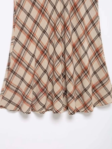 Detailed close-up of warm-toned plaid midi skirt with thick wool-like woven texture