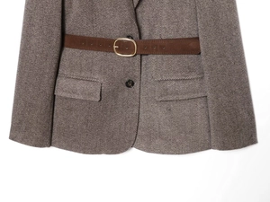 Détail de la veste à chevrons avec ceinture mate et boucle en métal doré de forme ovale