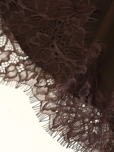Detailed close-up of dark brown eyelash lace with intricate floral mesh patterns