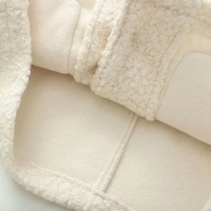 Close-up of cream bouclé fabric with a soft suede lining and flat seam stitching