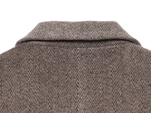 Gros plan du col d'un blazer en laine marron à chevrons montrant la texture et les coutures