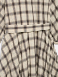Detailed macro view of beige plaid dress fabric with matching waist belt and cotton texture