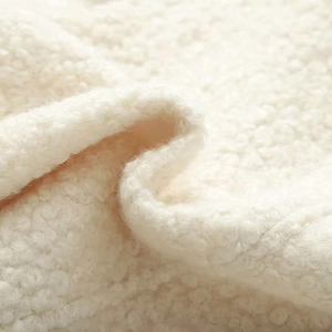 Detailed macro view of soft cream sherpa fleece fabric texture with curly wool pattern