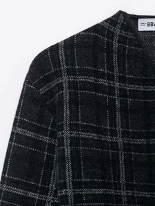 Détails de la maille grise à carreaux et de l'étiquette tissée sur l'épaule du vêtement