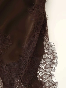 Detailed macro view of chocolate satin fabric with elegant eyelash lace trim detailing