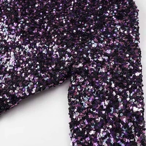 Detailed close-up of purple and black gradient sequins on the sleeve of the dress