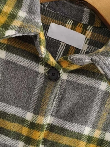 Close-up of lapel collar and button on a plaid flannel jacket in grey, green and yellow