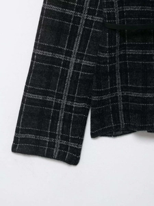 Détail du cardigan en maille à carreaux gris foncé avec une élégante ceinture noire fine
