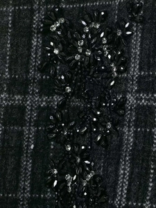 Gros plan de veste en tricot à carreaux avec broderies de perles noires et de sequins