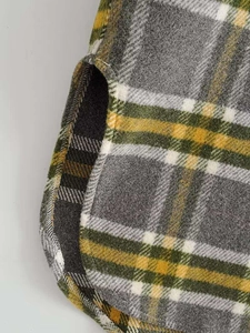 Detail of the curved hemline and side slit on a thick plaid wool blend jacket