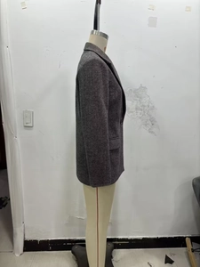 Detailed view of dark grey herringbone tweed texture on a women's formal blazer jacket