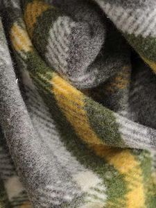 Close-up of soft plaid wool blend fabric showing ginger and green checkered texture