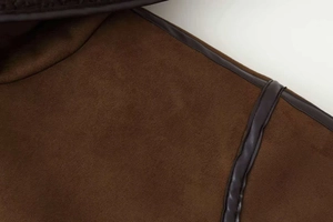 Detail of premium brown suede jacket featuring high-quality leather piping and fine stitching