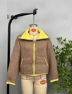 Detail of color-block knit jacket featuring brown body with yellow trims and dual pockets
