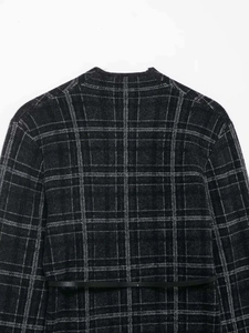 Vue détaillée de la texture tricotée à carreaux gris foncé et de la fine ceinture noire