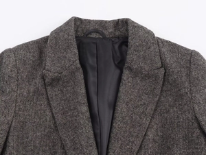 Detailed close-up of herringbone blazer with notched lapel and sleek black inner lining