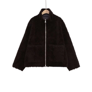 Détail d'une veste sherpa marron foncé avec fermeture éclair argentée et grandes poches