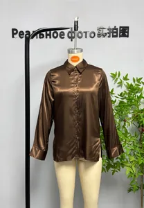 Detail view of brown satin shirt showing smooth glossy fabric and button closure