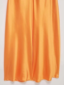 Gros plan détaillé de l'ourlet d'une robe midi en satin orange vif à texture soyeuse