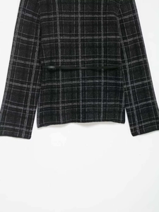 Détail d'un manteau en maille à carreaux gris foncé avec fine ceinture noire en cuir chic
