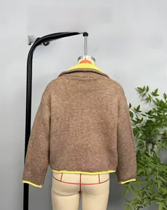 Detail of brown knit jacket featuring vibrant yellow contrast piping on the collar and cuffs