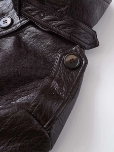 Detailed macro view of dark brown faux leather texture and vintage marble button on jacket